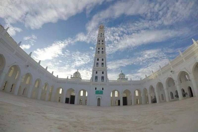 Al-Muhdaar Mosque daytime, wide-angle perspective of the Al-Mihdhar Mosque in Tarim, highlighting the prominent minaret and white architectural features against a clear sky.